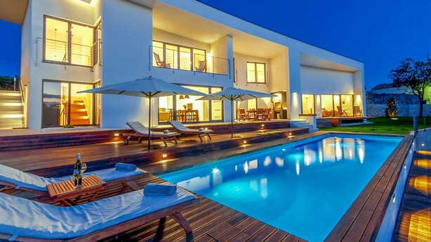 Une maison moderne à deux étages, dotée d’une piscine, d’un espace extérieur aménagé et d’un intérieur bien éclairé.