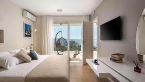 Ein modernes Hotelzimmer mit einem großen Bett, einem Flachbildfernseher, einem Balkon mit einer Hängematte und Blick aufs Meer.