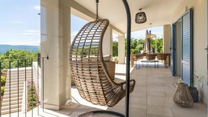 Una silla colgante en un balcón con vistas al exterior.