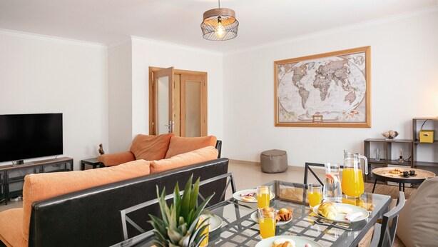 Un salon moderne avec un canapé, une table à manger où est servi le petit-déjeuner, un téléviseur et une carte du monde accrochée au mur.