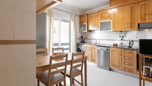 Une cuisine moderne dotée de meubles en bois, d’appareils électroménagers en acier inoxydable et d’un coin repas avec une table et des chaises.