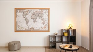 Une pièce avec une carte du monde accrochée au mur, une petite table ronde avec une lampe et une bibliothèque.