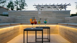 A modern outdoor seating area with a pergola structure and a stone wall backdrop. - Pet friendly home in Posedarje (Posedarje)