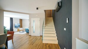 A modern living room with a wooden floor, a staircase with a unique design, and a television in the background. - Pet friendly home in Posedarje (Posedarje)
