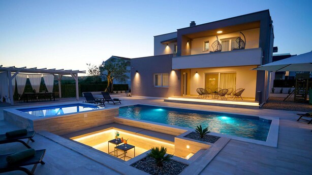 A modern two-story house with a swimming pool, outdoor seating, and a well-lit patio area. - Pet friendly home in Posedarje (Posedarje)