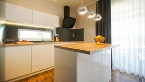 A modern kitchen with white cabinetry, a wooden countertop, a built-in oven, and pendant lights. - Pet friendly home in Posedarje (Posedarje)