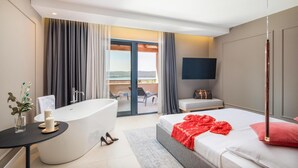 Ein modernes Hotelzimmer mit Badewanne, einem Bett, einem Fernseher und einem Balkon mit Blick.