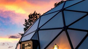 Estructura tipo cúpula geométrica con una puerta y una lámpara.