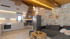A modern kitchen with a stone wall, a refrigerator, and a wooden ceiling.