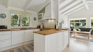 A spacious kitchen with white cabinetry, a wooden island, and large windows offering views of the outdoors. - Gorgeous home in Jerup with sauna (Jerup)
