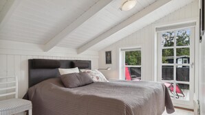 A bedroom with a large bed, a bench, and a window with a view of the outdoors. - Gorgeous home in Jerup with sauna (Jerup)