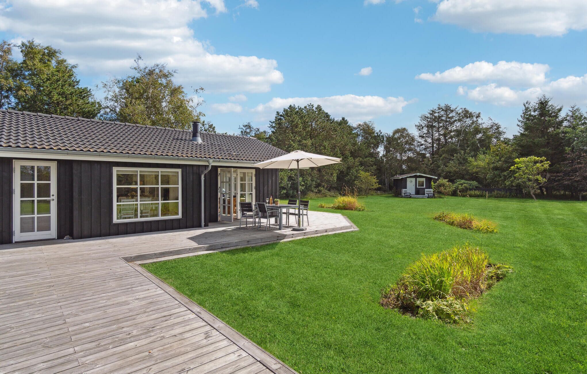 Een modern huis met een patio, een klein terras en een verzorgd gazon.