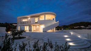A modern two-story house with a curved staircase leading to the upper floor, surrounded by a landscaped garden. - Amazing home in Gradina (Gradina)
