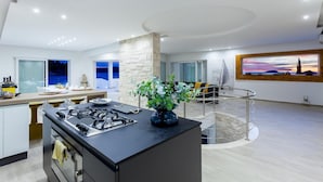 A modern kitchen with a central island, a dining area with a view, and a living space with a sailboat model. - Amazing home in Gradina (Gradina)