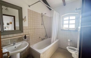 Ein Badezimmer mit Badewanne, Waschbecken, Toilette, Dusche und einem Fenster.