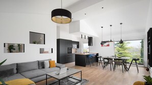 Un saló modern amb un sofà gris, una taula de centre i una zona de menjador amb taula i cadires.