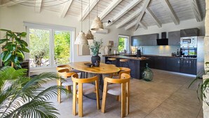 Une cuisine moderne dotée d’un îlot central, d’appareils électroménagers intégrés et d’un coin repas avec une table ronde et des chaises en bois.