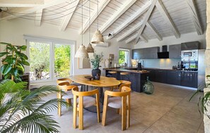 Eine moderne Küche mit Kochinsel, integrierten Geräten und einem Essbereich mit rundem Tisch und Holzsesseln.