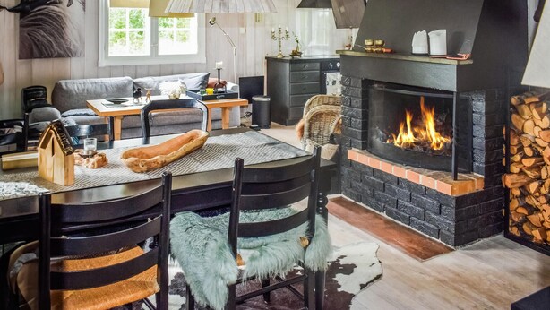 A cozy living room with a fireplace, a dining table with chairs, and a sofa. - 3 bedroom nice home in Gol (Gol)