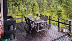 A wooden deck with a table and chairs, surrounded by a forest. - 3 bedroom nice home in Gol (Gol)
