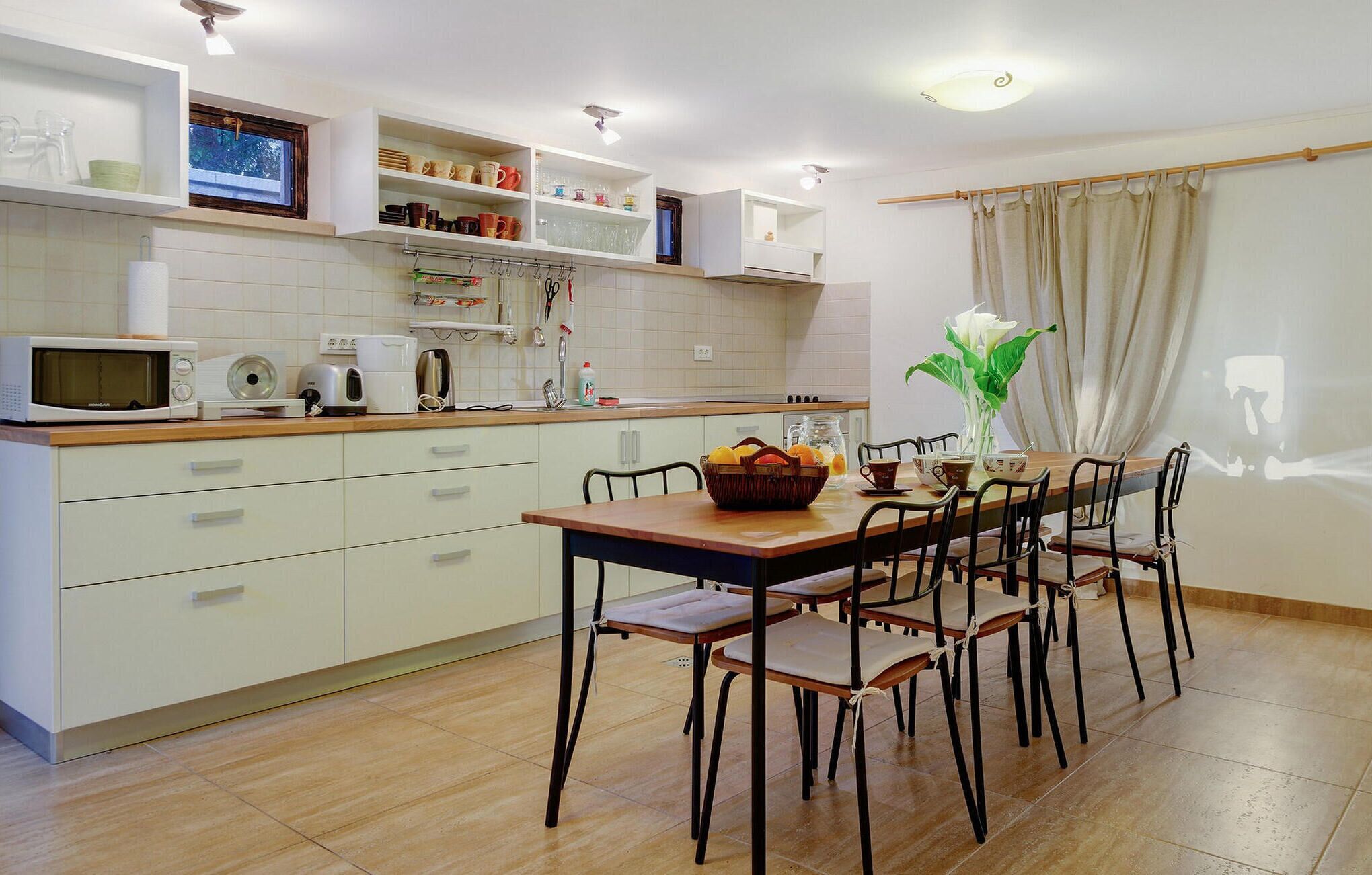 A modern kitchen with white cabinets, a microwave, toaster, and a dining area with a wooden table and chairs.