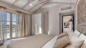 Ruime slaapkamer met een groot bed, uitzicht op het omliggende landschap en een modern plafondontwerp.