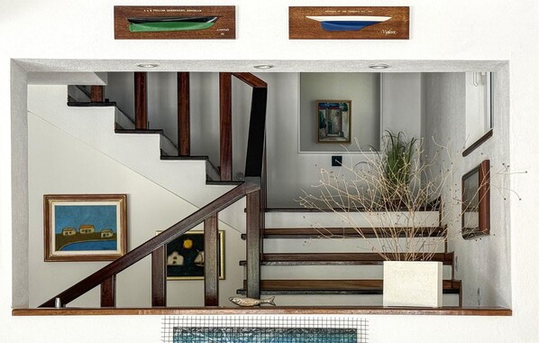 A staircase with wooden railings, a framed painting, and a potted plant.