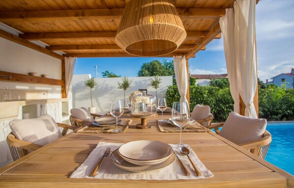 Enjoy a meal al fresco in this tranquil outdoor dining area, complete with a wooden table and wicker chairs.