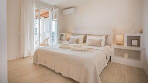 Un dormitori amb un llit, taules de nit, una làmpada al sostre i una finestra amb cortines.