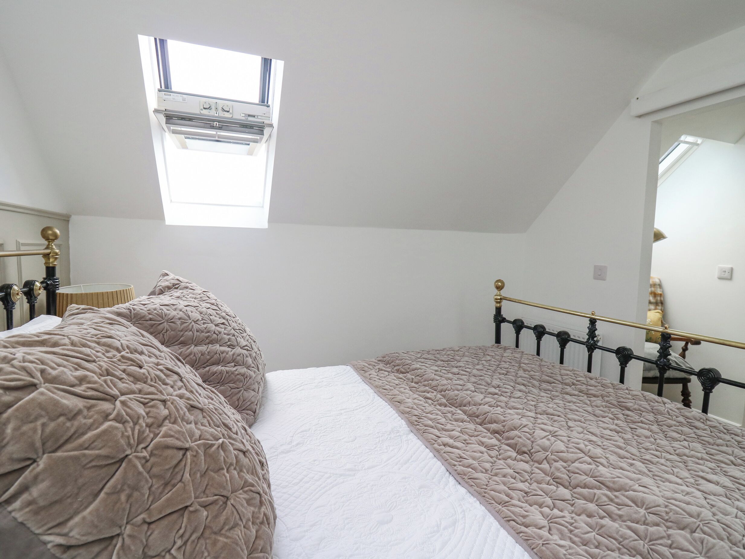 Un dormitorio con cama, ventana y espejo.
