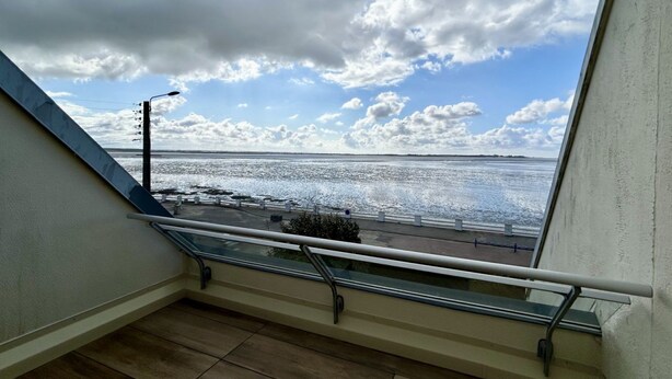 A balcony with a glass railing overlooking a waterfront. - Le Grand Large, 4-person apartment (Le Crotoy)