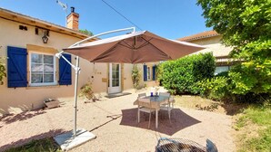 A patio with a table and chairs, a barbecue grill, and a covered area with a table and chairs.