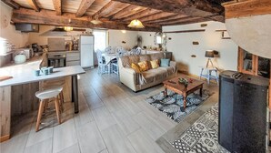 A spacious living area with a sofa, coffee table, and a fireplace. There is a kitchen area with a refrigerator and a dining table.