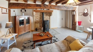 A cozy living room with a fireplace, wooden beams, a sofa, and a small table.