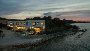 Una casa moderna a due piani con piscina, situata vicino all'acqua.