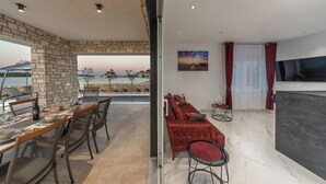 Un soggiorno moderno con un divano rosso, una televisione e un'area pranzo con tavolo e sedie.
