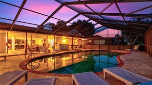 Une piscine couverte avec des chaises longues, un espace bar et une vue sur le coucher de soleil.