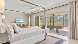 A spacious bedroom with a large bed, a television, and a view of the outdoors through a sliding glass door. - 5BR/4BA |Pool & Spa + Pickleball, Golf View (Sarasota)