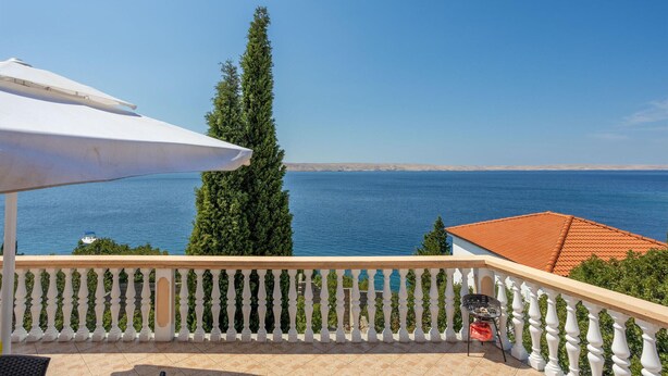 A balcony with a white railing, a white umbrella, and a grill. - 3 bedroom beautiful apartment in Baric Draga (Baric Draga)