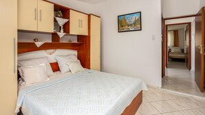 A bedroom with a bed, wooden wardrobe, and a painting on the wall. - 3 bedroom beautiful apartment in Baric Draga (Baric Draga)