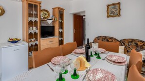 A dining area with a table set for four, a television, and a cabinet with glass doors. - 3 bedroom beautiful apartment in Baric Draga (Baric Draga)