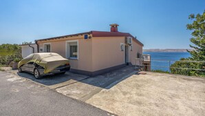 A small building with a car parked in front, a balcony, and a view of the sea. - 3 bedroom beautiful apartment in Baric Draga (Baric Draga)