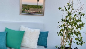 A white sofa with teal and white cushions, a wooden table, and a potted plant. - Masal Küçükköy Otel (Ayvalik)