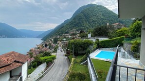 Un pueblo en una ladera con vistas despejadas al lago, una piscina y un camino que baja hacia el agua.