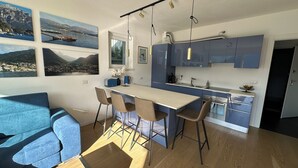 Una cocina moderna con una isla central, taburetes de bar y un rincón de comedor con un sofá azul.
