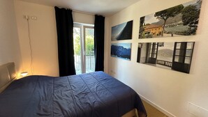 Un dormitorio con cama, ventana con cortinas y varias fotografías enmarcadas en la pared.