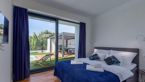 A bedroom with a large bed, a view of a pool and outdoor area, and a modern design.