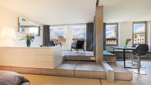 Habitación de hotel con balcón, comedor, sofá y escritorio.