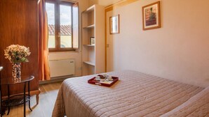 A bedroom with a bed, a bedside table with a vase, a window with curtains, and a tray with cups and a pastry. - Apartments Florence - Ariento Eva 1bdr San Lorenzo (Firenze)