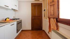 A kitchen with white cabinets, a stove, and a wooden door. - Apartments Florence - Ariento Eva 1bdr San Lorenzo (Firenze)